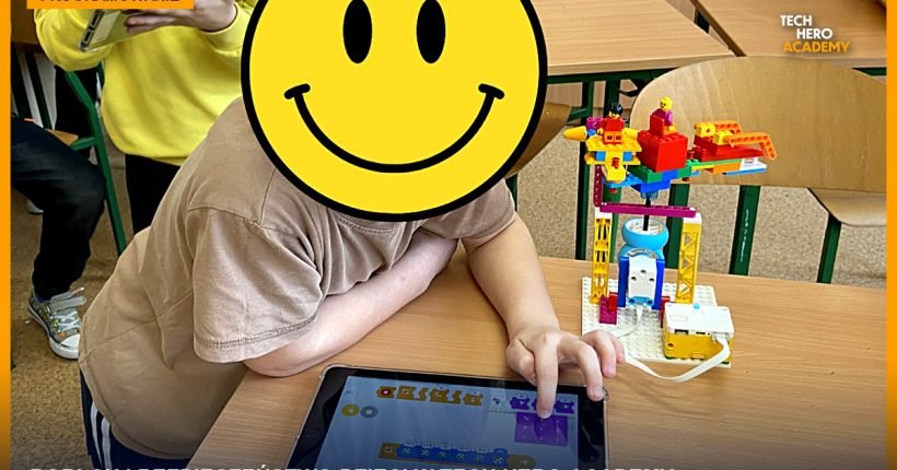 Dziecko programuje na tablecie obok robota LEGO, nauka Roblox Studio w Tech Hero Academy
