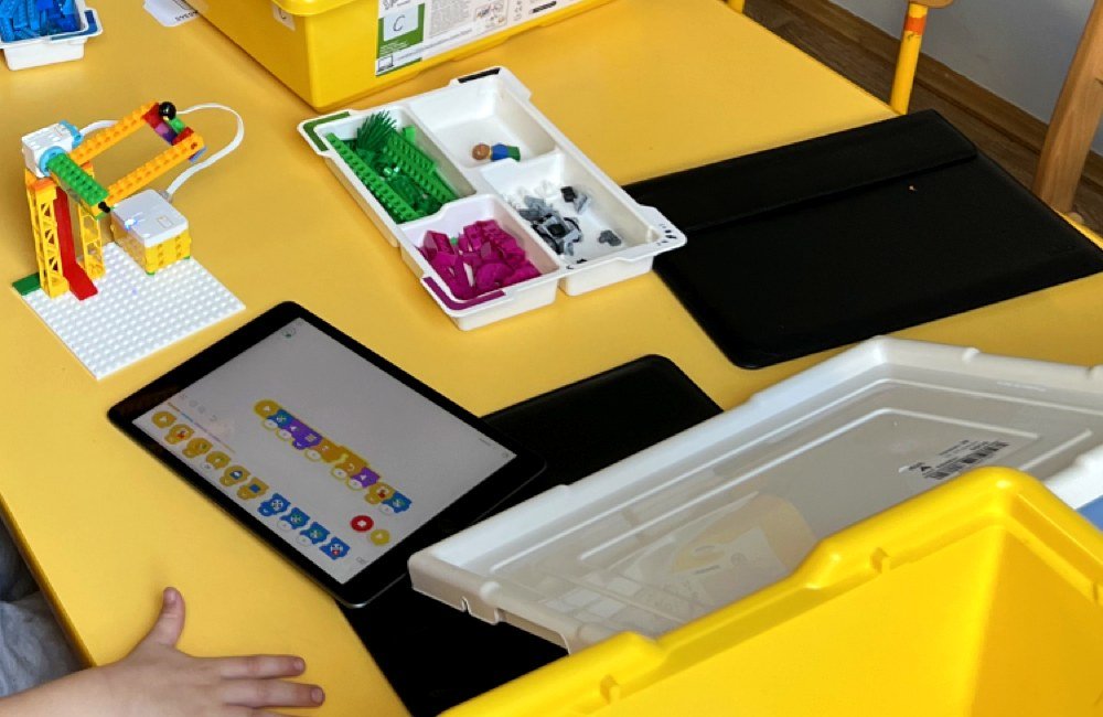 Tablet z aplikacją do kodowania blokowego obok skonstruowanego robota LEGO na zajęciach Tech Hero Academy