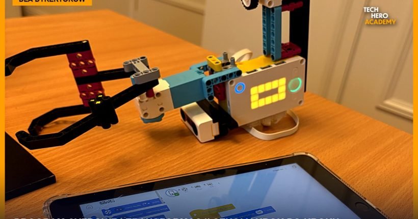 Robot z klocków LEGO SPIKE na biurku obok tabletu z programem ułożonym z bloków, materiał z zajęć Tech Hero Academy