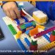 Dziecko buduje konstrukcję z klocków LEGO, obok tablet z programem ułożonym z bloków, zajęcia Tech Hero Academy