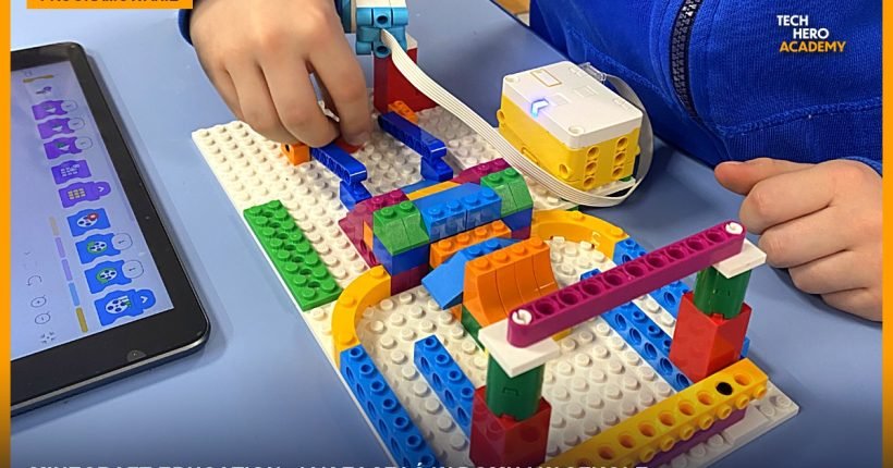 Dziecko buduje konstrukcję z klocków LEGO, obok tablet z programem ułożonym z bloków, zajęcia Tech Hero Academy