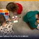 Troje dzieci na podłodze buduje modele z klocków LEGO i programuje je na tabletach podczas półkolonii Tech Hero Academy