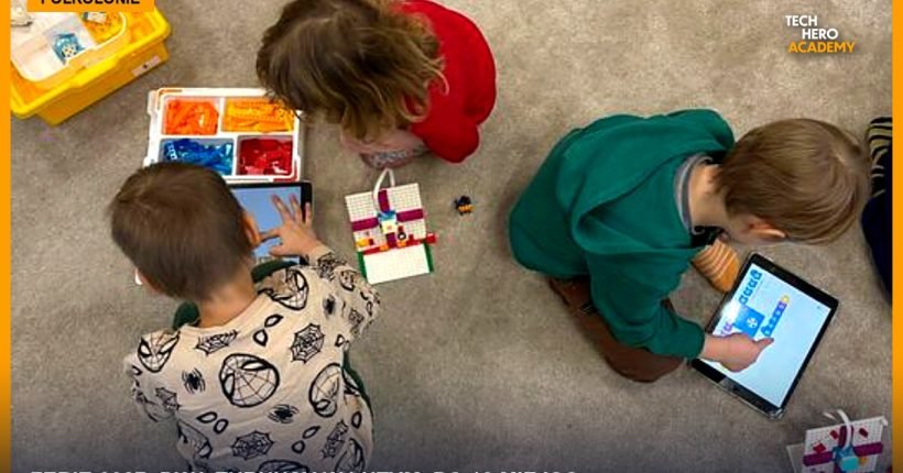 Troje dzieci na podłodze buduje modele z klocków LEGO i programuje je na tabletach podczas półkolonii Tech Hero Academy