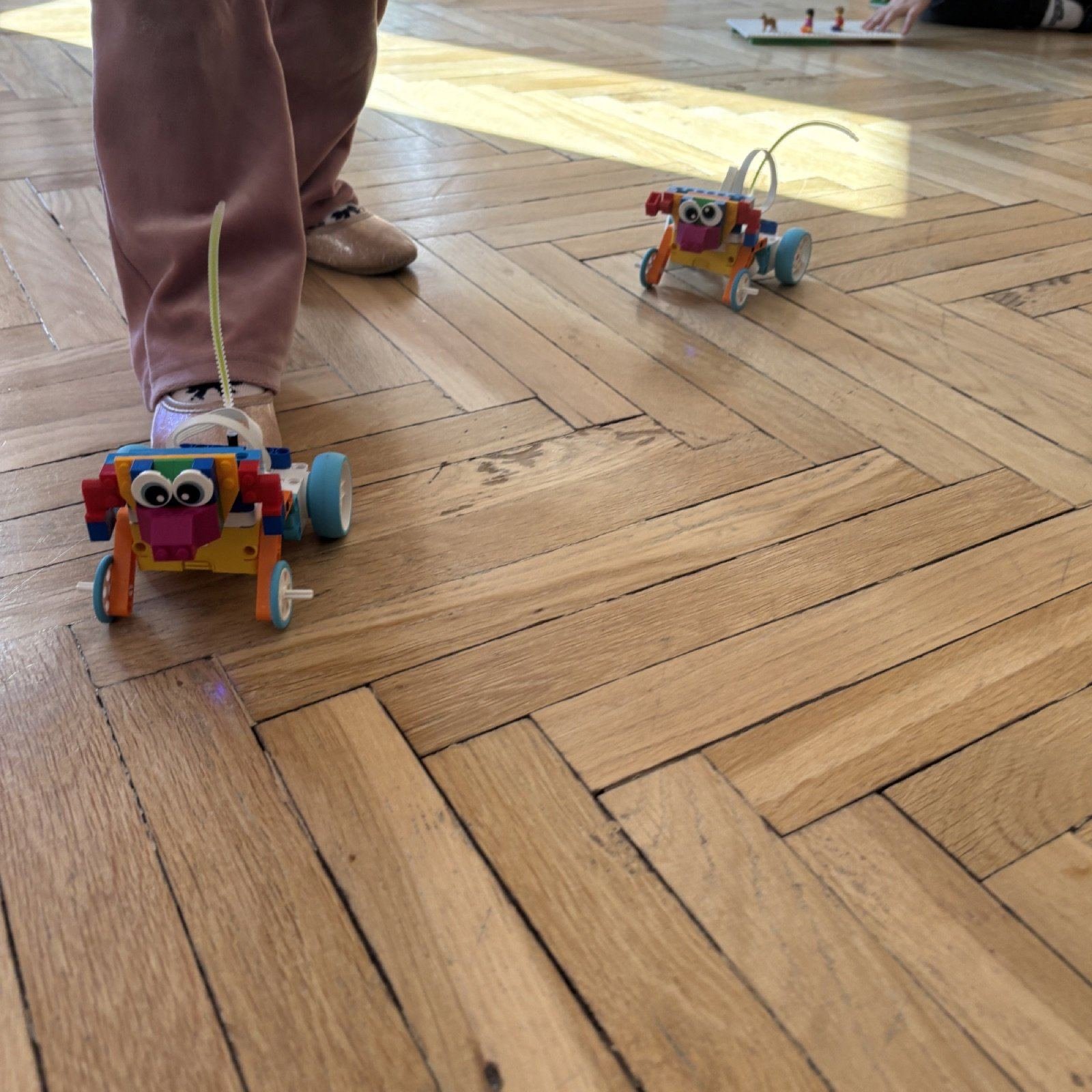 Półkolonie Tech Hero Academy: dwa roboty z klocków jadą po parkiecie