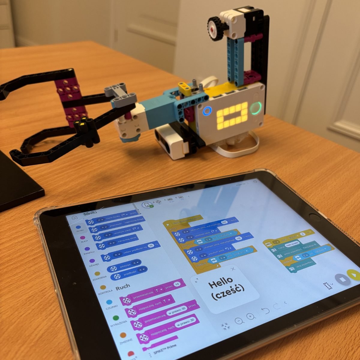 Pracownia informatyczna w szkole: tablet z programem w blokach obok robota z klocków LEGO