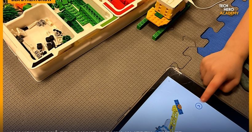 Skrzynka klocków LEGO Education, konstrukcja z silnikiem i tablet z instrukcją budowy na zajęciach, dłoń dziecka wskazuje ekran